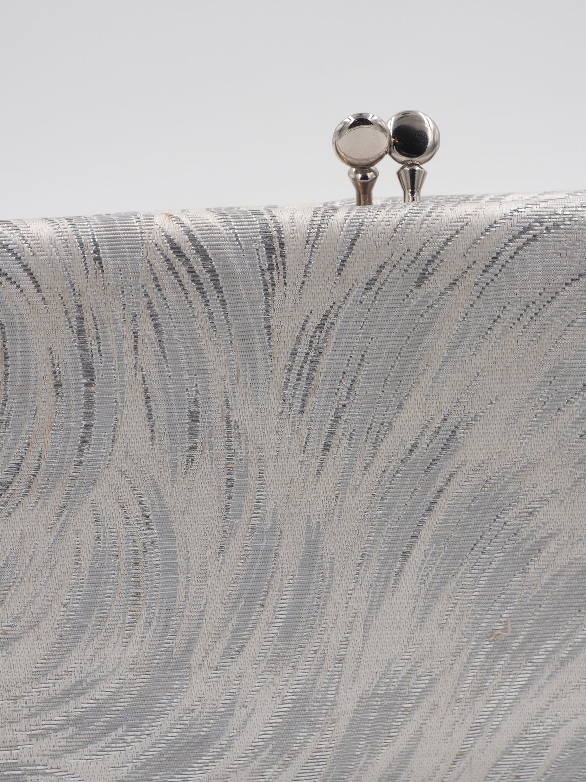 A rectangular clutch purse with a textured, wavy pattern in silver and white, featuring a small silver metal clasp at the top