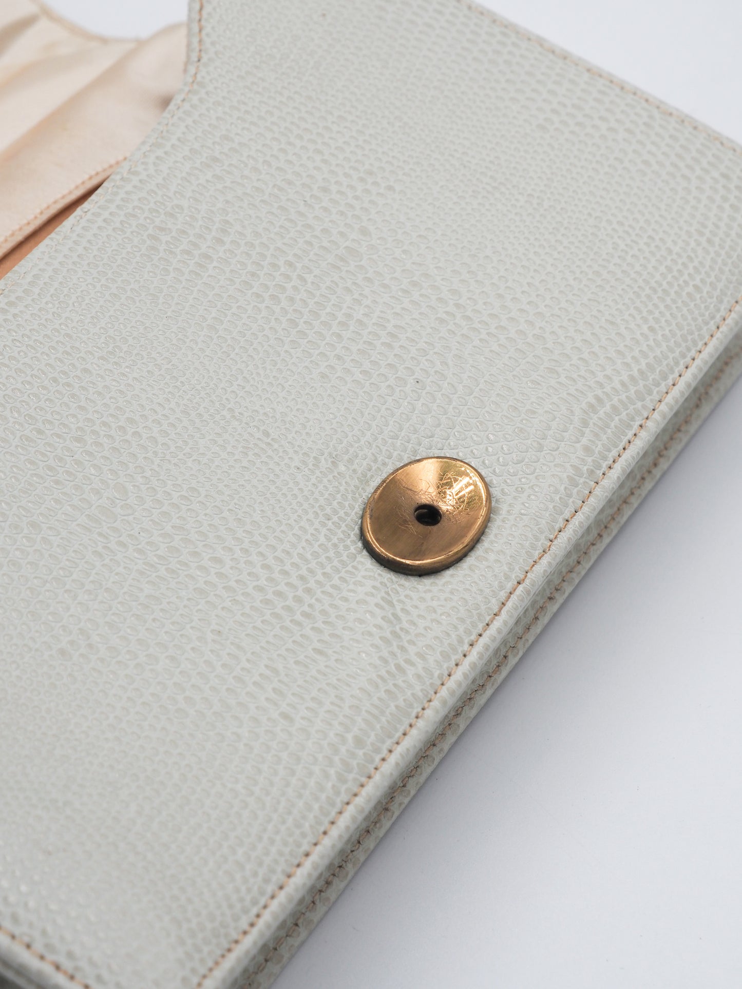 A vintage white lizard textured leather clutch handbag with a braided tan rope handle and gold-toned metal accents